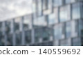 Abstract blurred modern corporate business glass office building exterior featuring repeating geometric square windows reflecting cloudy sky creating city architecture background 140559692