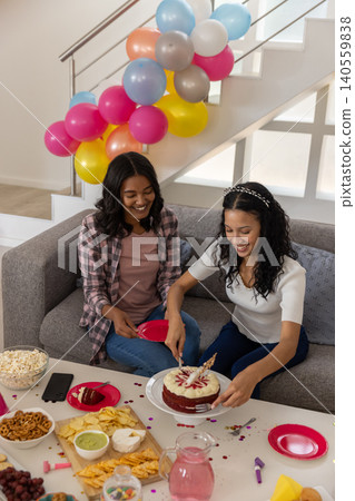 Mom and teenage daughter celebrating birthday on couch at home with red velvet cake Mom and teenage daughter celebrating birthday on couch at home with red velvet cake 140559838