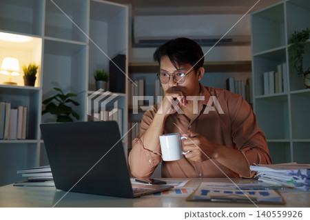 Asian man in his 20s working on laptop at home office with coffee 140559926