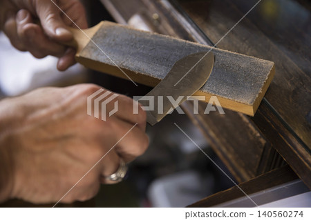 A hunter sharpening a hunting knife. A hunter sharpening a hunting knife. 140560274