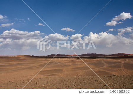 A dirt and gravel track leads towards the fine sand hills of the Merzouga Desert in Morocco. A dirt and gravel track leads towards the fine sand hills of the Merzouga Desert in Morocco. 140560292