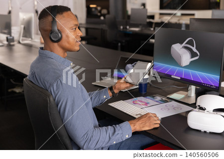 Mid adult african american man holding tablet, viewing vr headset unit at office desk Mid adult african american man holding tablet, viewing vr headset unit at office desk 140560506