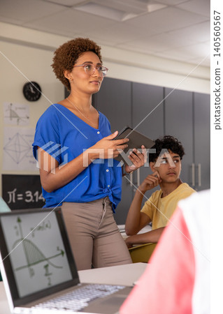 Female teacher holding tablet, speaking as teenage student listening at classroom desk Female teacher holding tablet, speaking as teenage student listening at classroom desk 140560567