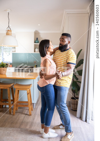 Diverse couple dancing and swaying in modern kitchen around island under pendant light Diverse couple dancing and swaying in modern kitchen around island under pendant light 140560603