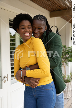 African american couple hugging on porch under wicker canopy beside shuttered french door African american couple hugging on porch under wicker canopy beside shuttered french door 140560627