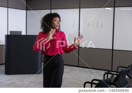 African american woman in business attire presenting chart on screens and gesturing at podium African american woman in business attire presenting chart on screens and gesturing at podium 140560690