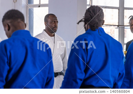 Four african american men practicing karate in gym with white gi, blue gis, black belt Four african american men practicing karate in gym with white gi, blue gis, black belt 140560804