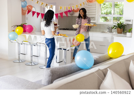Diverse mom and teenage daughter sharing snacks in kitchen with cupcakes and popcorn, copy space Diverse mom and teenage daughter sharing snacks in kitchen with cupcakes and popcorn, copy space 140560922
