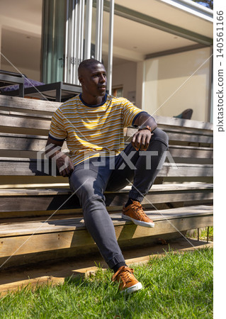 African american adult male sitting on wood deck steps outside home African american adult male sitting on wood deck steps outside home 140561166