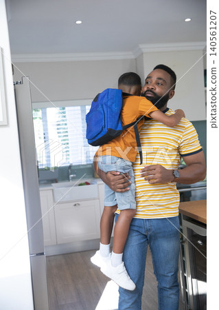 African American father and son hugging in home kitchen with blue backpack, copy space African American father and son hugging in home kitchen with blue backpack, copy space 140561207