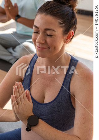 Mid adult female and male sitting on yoga mats at yoga studio wearing sportswear and smartwatch Mid adult female and male sitting on yoga mats at yoga studio wearing sportswear and smartwatch 140561256