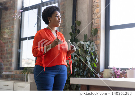 African american woman standing in modern office presenting chart on glass panel with marker African american woman standing in modern office presenting chart on glass panel with marker 140561293