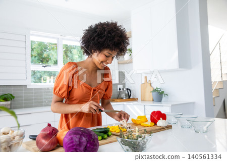 African american woman slicing mushrooms on cutting board at kitchen island African american woman slicing mushrooms on cutting board at kitchen island 140561334
