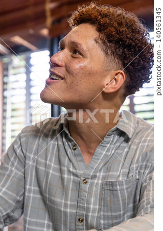 Man sitting in room with wooden ceiling beams, gazing upward through horizontal blinds Man sitting in room with wooden ceiling beams, gazing upward through horizontal blinds 140561345