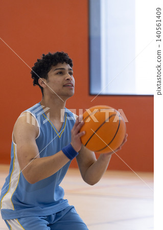 African american man in light blue uniform holding orange basketball preparing free throw on gym African american man in light blue uniform holding orange basketball preparing free throw on gym 140561409