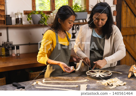 Diverse mother and daughter crafting lattice on fruit tart using pastry strips in farmhouse kitchen Diverse mother and daughter crafting lattice on fruit tart using pastry strips in farmhouse kitchen 140561464