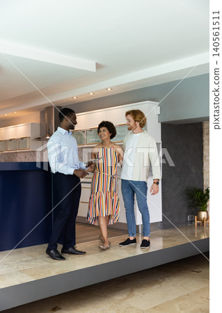 Diverse group discussing backsplash details in kitchen near navy-blue island with smartphone Diverse group discussing backsplash details in kitchen near navy-blue island with smartphone 140561511