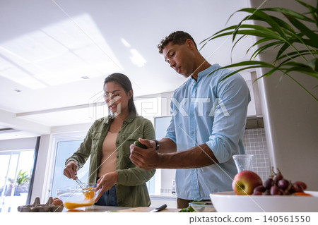 Diverse couple whisking eggs, slicing avocado at kitchen island with fresh produce display Diverse couple whisking eggs, slicing avocado at kitchen island with fresh produce display 140561550
