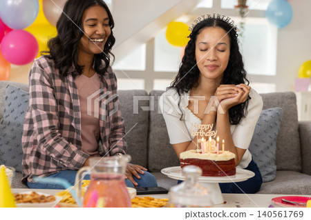 Diverse mom and teenage daughter celebrating birthday on grey couch with red velvet cake Diverse mom and teenage daughter celebrating birthday on grey couch with red velvet cake 140561769