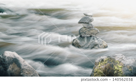 Stack of balanced Zen stones standing in a fast flowing river with long exposure motion blur Stack of balanced Zen stones standing in a fast flowing river with long exposure motion blur 140562038