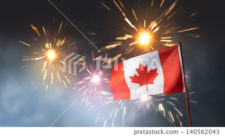 The national flag of Canada waving on a flagpole against a backdrop of bright, colorful fireworks exploding in the night sky during a celebration The national flag of Canada waving on a flagpole against a backdrop of bright, colorful fireworks exploding in the night sky during a celebration 140562043