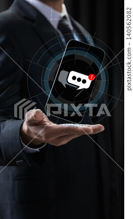 Businessman holding a floating holographic smartphone with a chat message notification icon, symbolizing digital communication and modern business connectivity Businessman holding a floating holographic smartphone with a chat message notification icon, symbolizing digital communication and modern business connectivity 140562082