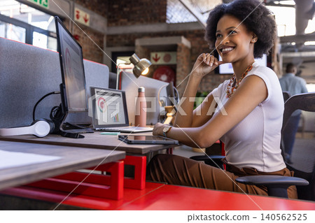 African american woman in smiling, resting chin at office desk with monitor, copy space African american woman in smiling, resting chin at office desk with monitor, copy space 140562525