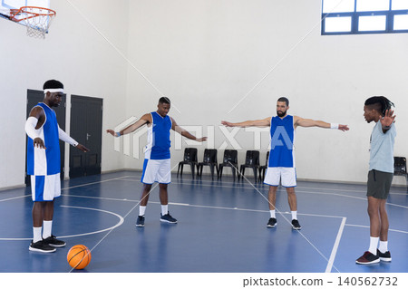 Diverse male teammates doing warm-up drill on gym basketball court with ball and hoop Diverse male teammates doing warm-up drill on gym basketball court with ball and hoop 140562732