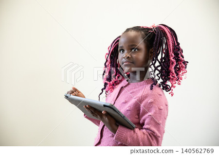 African american girl in pink sweater holding and tapping tablet against wall, copy space African american girl in pink sweater holding and tapping tablet against wall, copy space 140562769
