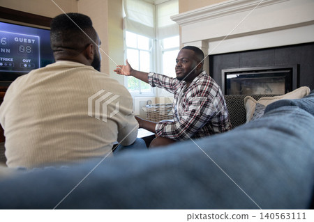 African american male friends discussing baseball on couch at home while watching tv scoreboard 140563111