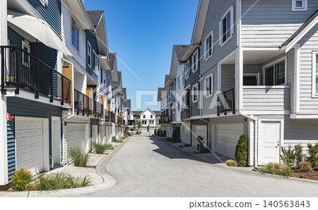 New townhouses in residential comfortable neighborhood on a sunny day. Real Estate Exterior Front Homes with garages in suburbs North America. Modern apartment buildings. Housing development New townhouses in residential comfortable neighborhood on a sunny day. Real Estate Exterior Front Homes with garages in suburbs North America. Modern apartment buildings. Housing development 140563843
