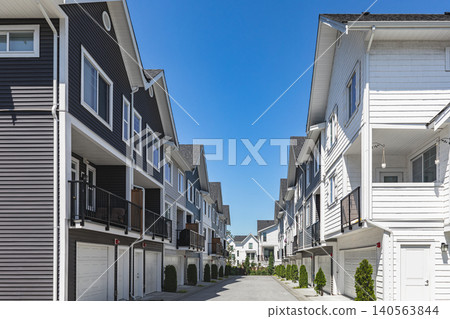 New townhouses in residential comfortable neighborhood on a sunny day. Real Estate Exterior Front Homes with garages in suburbs North America. Modern apartment buildings. Housing development New townhouses in residential comfortable neighborhood on a sunny day. Real Estate Exterior Front Homes with garages in suburbs North America. Modern apartment buildings. Housing development 140563844
