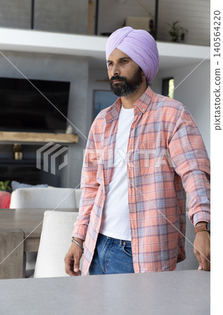 Indian man standing behind light gray countertop in modern living area with tv Indian man standing behind light gray countertop in modern living area with tv 140564220