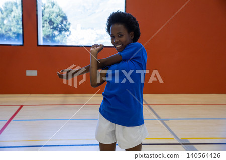 African american child stretching arm across chest on gym floor with court lines wearing shirt African american child stretching arm across chest on gym floor with court lines wearing shirt 140564426