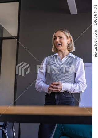 Professional woman standing and presenting at conference room table with flip chart Professional woman standing and presenting at conference room table with flip chart 140564473