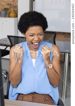 African American woman sitting at office desk using computer monitor and whiteboard African American woman sitting at office desk using computer monitor and whiteboard 140564487