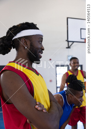 African american men standing on court wearing jerseys with sweatband under hoop, copy space African american men standing on court wearing jerseys with sweatband under hoop, copy space 140564513