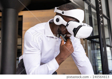 African american man leaning and resting chin in wood-paneled office, wearing vr headset African american man leaning and resting chin in wood-paneled office, wearing vr headset 140564813