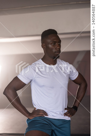 African American man standing in gym wearing performance shirt and smartwatch on rubber mat African American man standing in gym wearing performance shirt and smartwatch on rubber mat 140564887