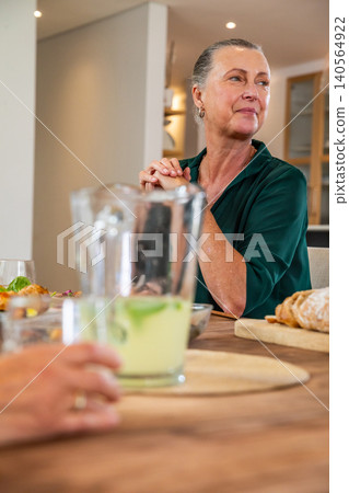 Senior friends sitting at table in kitchen having salad, bread and lime drink, copy space Senior friends sitting at table in kitchen having salad, bread and lime drink, copy space 140564922