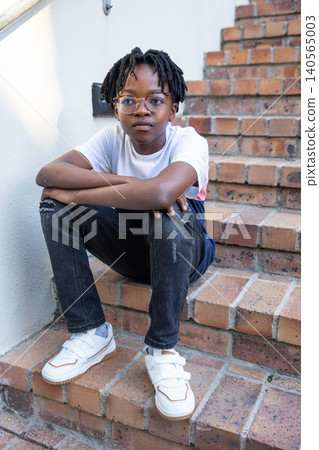 African american male teenager sitting on brick steps wearing glasses and sneakers African american male teenager sitting on brick steps wearing glasses and sneakers 140565003