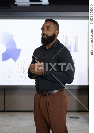 African american man in black shirt presenting charts on projection screen in meeting room 140565009