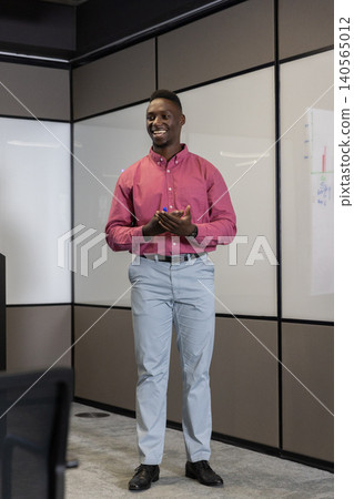 African american man smiling and presenting charts on whiteboard with blue marker in meeting room African american man smiling and presenting charts on whiteboard with blue marker in meeting room 140565012