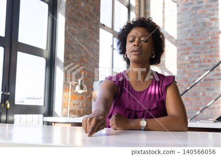 African american woman pointing at white desk near lamp wearing blouse, wristwatch, copy space African american woman pointing at white desk near lamp wearing blouse, wristwatch, copy space 140566056