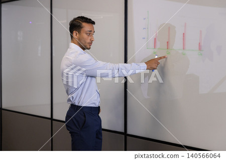 Asian man in business attire presenting bar chart using blue marker in meeting room, copy space Asian man in business attire presenting bar chart using blue marker in meeting room, copy space 140566064