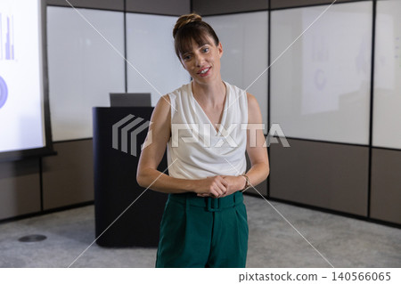 Woman presenter standing at black lectern in meeting room presenting charts on projector screen Woman presenter standing at black lectern in meeting room presenting charts on projector screen 140566065