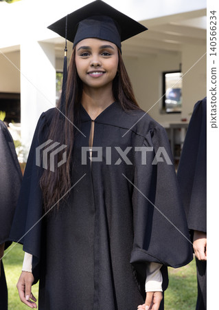 South asian woman standing on lawn in front of campus columns wearing black gown, mortarboard South asian woman standing on lawn in front of campus columns wearing black gown, mortarboard 140566234
