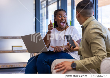 Diverse coworkers exchanging ideas on bench in office lounge with laptop, smartphone, copy space Diverse coworkers exchanging ideas on bench in office lounge with laptop, smartphone, copy space 140566286