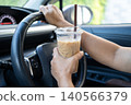 Asian lady holding ice coffee to eat in car, dangerous and risk an accident. 140566379