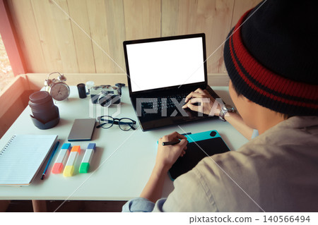 Back of freelance man graphic designer working on a digital laptop, with mock-up white screen for use. work from home office using a graphic tablet. Soft focus blur Back of freelance man graphic designer working on a digital laptop, with mock-up white screen for use. work from home office using a graphic tablet. Soft focus blur 140566494